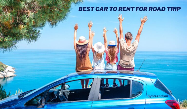 A group of four friends, two men and two women, sit on the roof of a blue car with their arms raised, enjoying a scenic ocean view. The car is parked near a coastal cliff with clear blue skies and water in the background. The text "BEST CAR TO RENT FOR ROAD TRIP" is written in bold at the top, and "Sylveer.com" is displayed on the car's side.