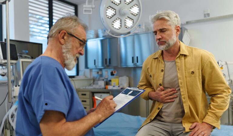 “Older man consulting a doctor about stomach pain during a medical examination in a modern clinic.” Health Concerns