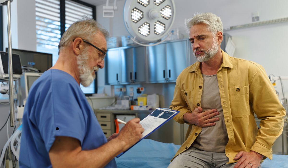 “Older man consulting a doctor about stomach pain during a medical examination in a modern clinic.” Health Concerns